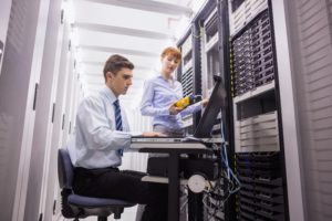 Team of technicians using digital cable analyser on servers in large data center